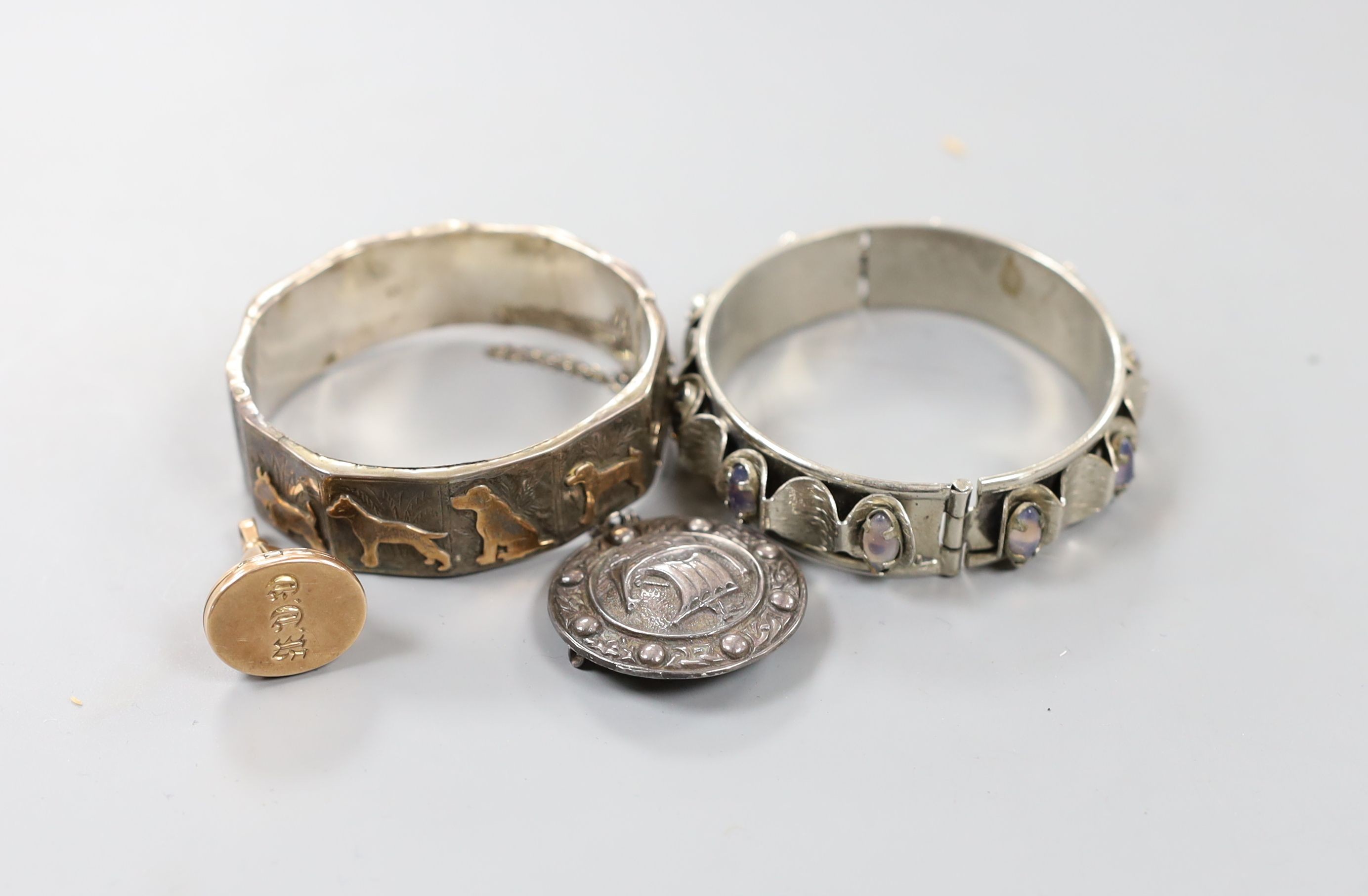 A late Victorian yellow metal overlaid fob seal pendant locket, engraved with initials, 28mm, a Scottish silver 'ship' brooch and two bangles including silver with yellow metal dog appliques.
